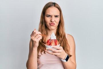 Young blonde woman eating strawberry ice cream skeptic and nervous, frowning upset because of problem. negative person.