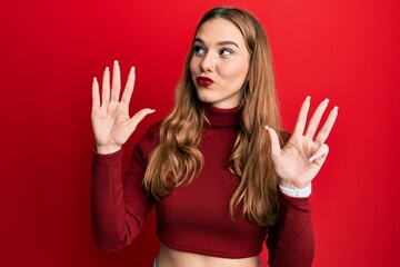 Young blonde woman wearing turtleneck sweater showing and pointing up with fingers number nine...