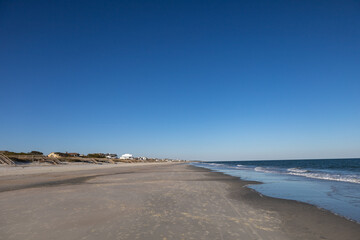 Fototapeta na wymiar Empty Litchfield beach, South Carolina. Housing and visible people in far distance