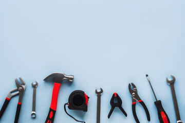 Working tools hammer, screwdriver, pliers, spanner and meter on light blue background, top view,...