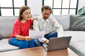 Middle age man and woman couple smiling confident using laptop working at home