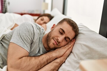 Young caucasian couple sleeping on bed at home.