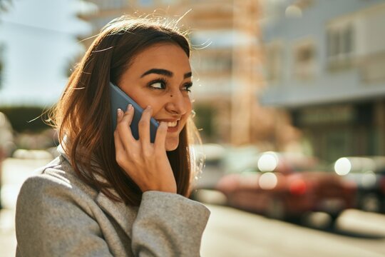 Young hispanic girl smiling happy talking on the smartphone at the city.