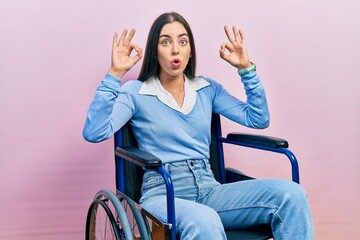 Beautiful woman with blue eyes sitting on wheelchair looking surprised and shocked doing ok...