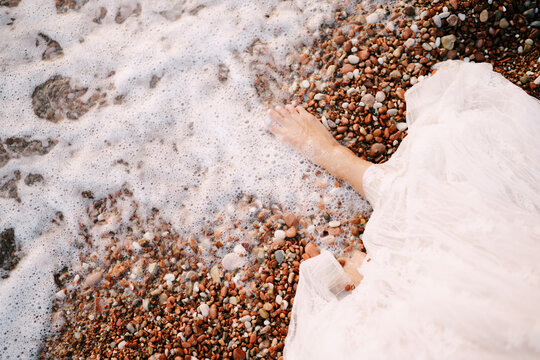Bare feet of the bride on a pebble beach washed by sea water © Nadtochiy