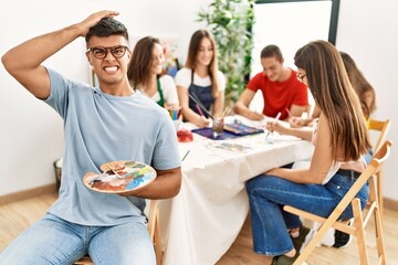 Young artist man drawing at art studio stressed and frustrated with hand on head, surprised and angry face