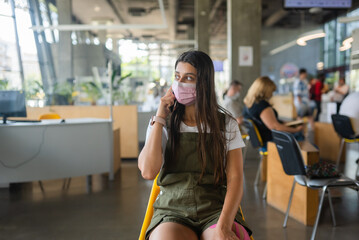 Young woman in face mask talking on mobile phone at indoor.