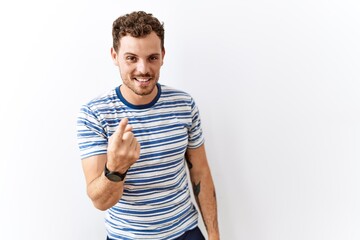 Fototapeta premium Handsome young man standing over isolated background beckoning come here gesture with hand inviting welcoming happy and smiling