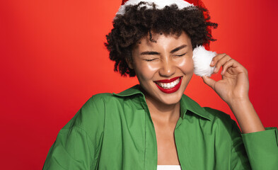 New Year and women beauty. Happy african american girl celebrates christmas, wearing santa hat and smiling, laughing carefree, standing over red background