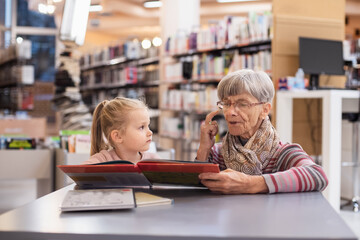 Grandmother reads a book to her granddaughter in the library