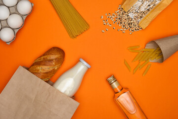 Bread and bottle of milk in paper bag. Eggs, spaghetti, pasta feathers, beans and bottle of olive...
