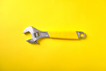 Metallic adjustable wrench on yellow background