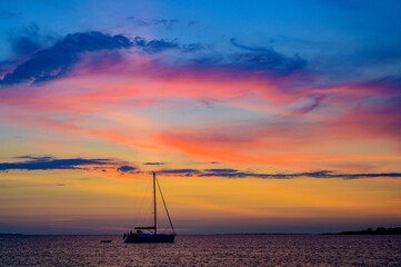 Segelboot vor Anker mit einem spektakulären, farbigen Sonnenuntergang