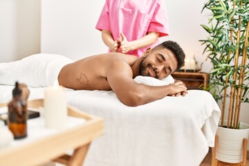 Obraz na płótnie Canvas Young african american smiling happy reciving back massage at beauty center.