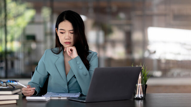Image of an Asian woman who is tired and overthinking from working with a tablet at the office.