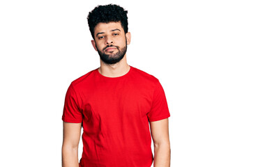 Young arab man with beard wearing casual red t shirt relaxed with serious expression on face. simple and natural looking at the camera.