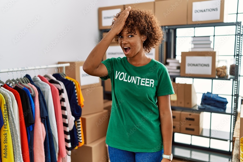 Sticker young african american woman wearing volunteer t shirt at donations stand surprised with hand on hea