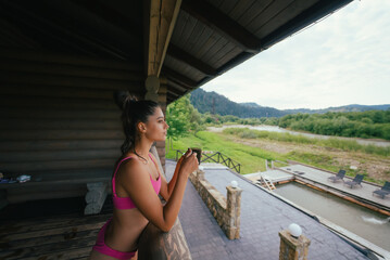 Side view portrait of a happy woman in pink swimsuit with coffee cup