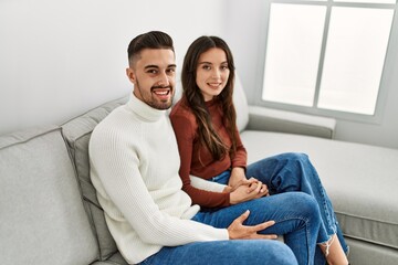 Obraz premium Young hispanic couple hugging and resting on the sofa and at home.