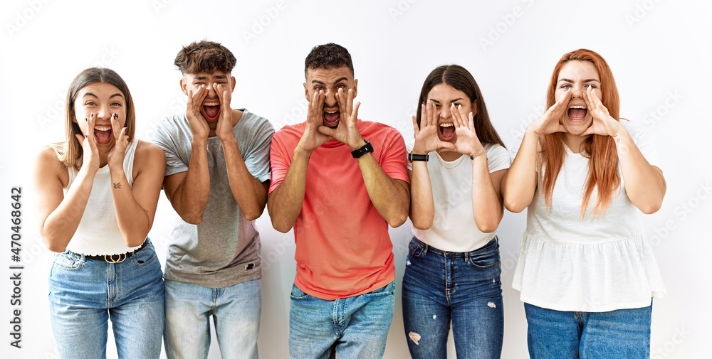 Sticker Group of young friends standing together over isolated background shouting angry out loud with hands over mouth