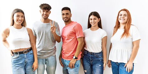 Group of young friends standing together over isolated background showing and pointing up with fingers number two while smiling confident and happy.