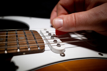 Fototapeta premium an electric guitar is played with a red pick