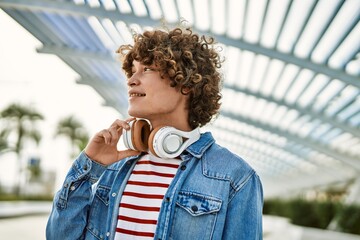 Young hispanic man wearing headphones at the city