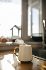 Mug of coffee on the table in the kitchen in front of the window