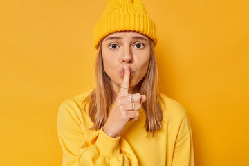 Photo of worried young female model makes shush gesture presses index finger to lips tells to be...