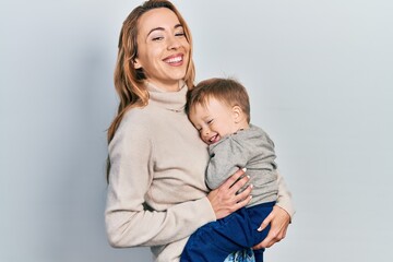 Young caucasian woman holding and hugging her son with love. Family of two bonding together. Mother holding infant toddler