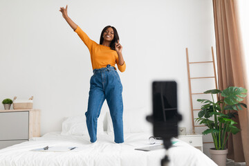 Fototapeta na wymiar African Woman Making Video On Cellphone Dancing On Bed Indoor