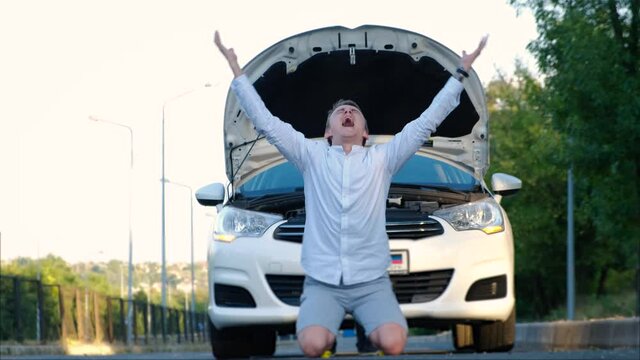 A desperate driver in front of a broken car emotionally experiences the situation