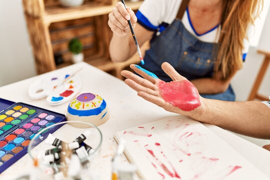 Couple painting hands at art studio.