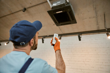 Male worker checking air conditioner in restaurant