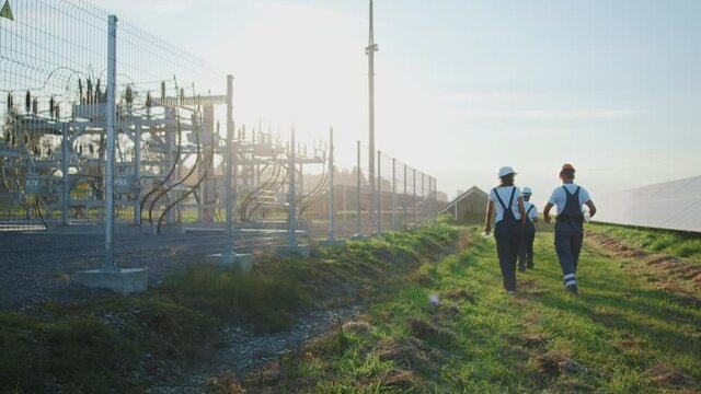 Solar station. Group of male and female industrial engineer workers walking on electric field power plant construction. Teamwork. Ecology.