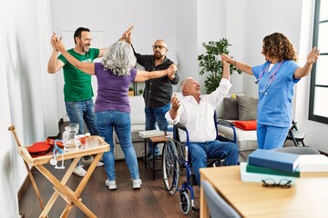 Group of retired people having party dancing with doctor and volunteer at nurse home.