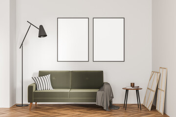 Two empty canvases on light beige wall and green sofa