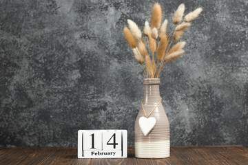 Valentine's Day card with a white cube calendar with the date of February 14 and a vase with lagurus (hare tails).