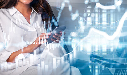 Businesswoman in white shirt with smart phone in hands, touching the screen in order to trade successfully. Concept of stock market behavior. Hologram financial graphs.