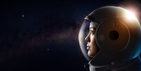 Head shot of attractive female astronaut wearing a helmet in outer space looking at planet earth....