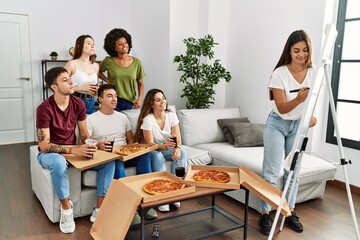 Group of young friends eating pizza and playing draw game at home.