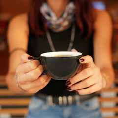 Woman handing coffee standing in black mug in her hand
