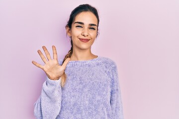 Young hispanic girl wearing casual clothes showing and pointing up with fingers number five while...