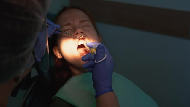 Dentist using mouth mirror and medicine syringe. Doctor treating a patient in a dental clinic