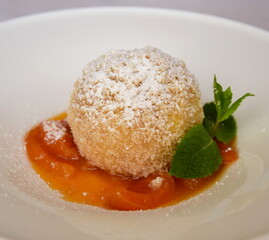 Marillenknödel mit Marillenröster, Staubzucker und Semmelbrösel auf weißen Teller. Traditionelle Nachspeise aus Südtirol und Österreich	