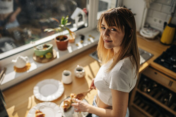 Young attractive girl in the kitchen with croissants in a white T-shirt and jeans