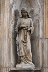 An old, weathered female sandstone angel in front of an old crypt in Berlin-Germany.