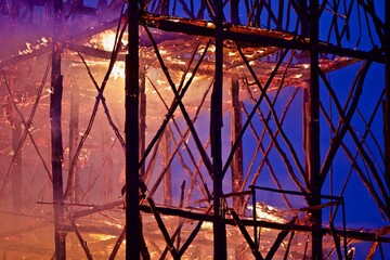 Burning wooden buildings close-up. Raging flames of fire. Firestorm closeup. Building is on fire. Bright inferno flames. Hell fire. Burning constructions background. Intense combustion and heat.