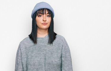 Young hispanic woman wearing cute wool cap relaxed with serious expression on face. simple and natural looking at the camera.