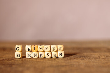 Konzept für 2G Regel: Geimpft, Genesen Schriftzug aus Holzwürfeln
